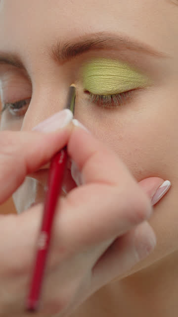 Makeup artist applies eye makeup to a girl.
