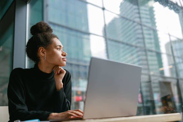 istock Female freelancer working on laptop while sitting in cafe and looking on window. Distance work 1467668021