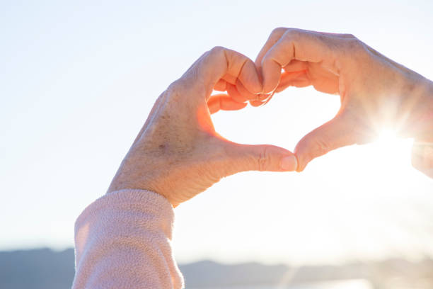 istock Close-up view of woman's hands framing sunrise, heart shape 1467670176