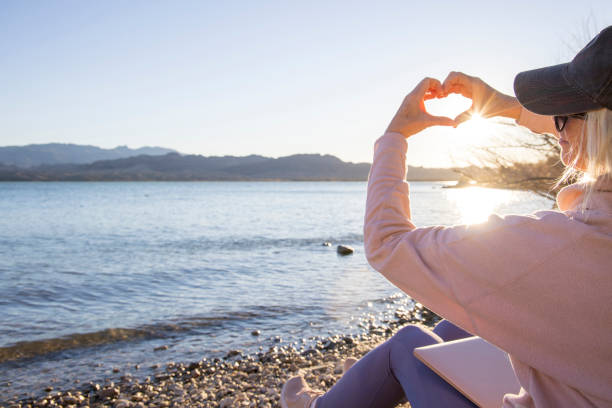 istock Medium distance view of woman's hands framing sunrise, heart shape 1467670216
