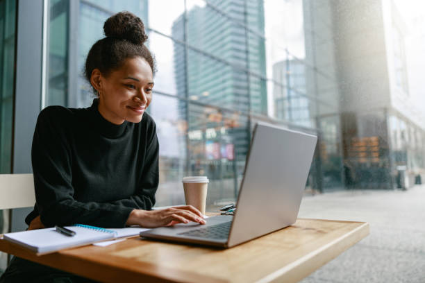 istock Smiling female freelancer working on laptop while sitting in cafe near window. Distance work 1467670410