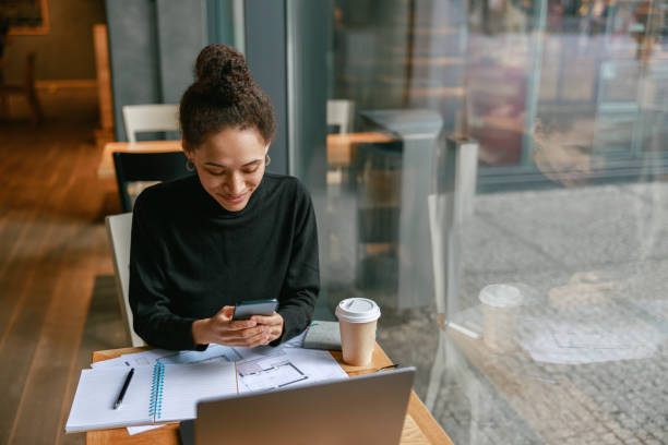 istock Woman architect use phone during working in cafe sitting near window. Distance work concept 1467670514