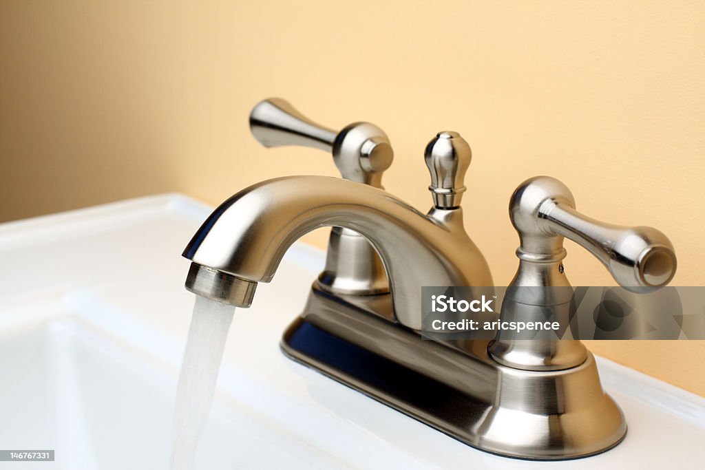 Acqua che scorre da un rubinetto in Nickel spazzolato porcellana Lavandino del bagno - Foto stock royalty-free di Rubinetto