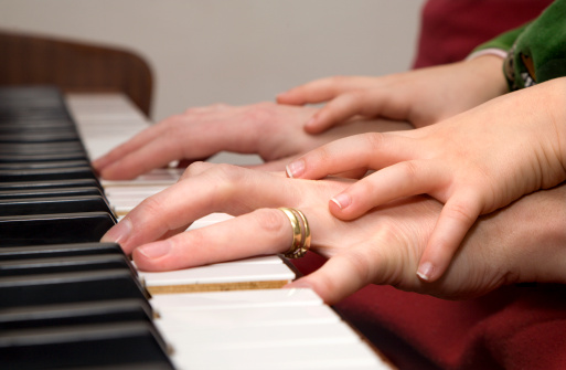 hands of mother and child by piano playing