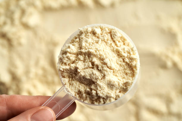 whey protein powder in a measuring cup in a hand - protein concentrate imagens e fotografias de stock