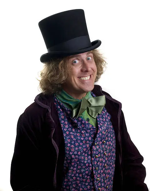 Wacky guy posing in Mad Hatter costume on white background.