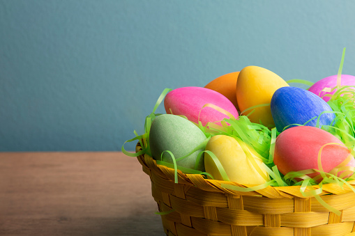 A close up of several colored Easter eggs in a basket.