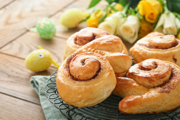 Easter breakfast Holliday concept. Easter bunny buns rolls with cinnamon made from yeast dough with orange glaze, easter decorations, colored eggs on old wooden background. Easter Holliday card. desayuno de pascua concepto holliday. rollos de bollos de conejo de pascua con canela hechos de masa de levadura con glaseado de naranja, decoraciones de pascua, huevos de colores sobre fondo de madera vieja. tarjeta de vacaciones de pascua.