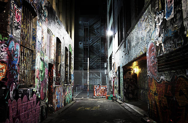 Dark Melbourne alleyway filled with graffiti One of numerous alleyways in Melbourne city, full of graffiti, obscure and intimidating. At the centre of the shot steel fire escape stairs can be seen. alley stock pictures, royalty-free photos & images