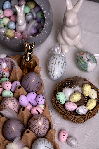 photo many colored decorative chicken and quail eggs and a ceramic white rabbit