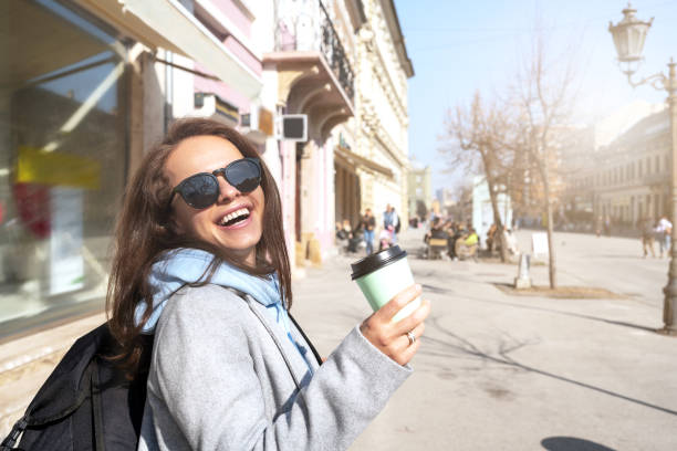 istock Woman with backpack holding coffee cup in hand while walking around the city. 1467680422