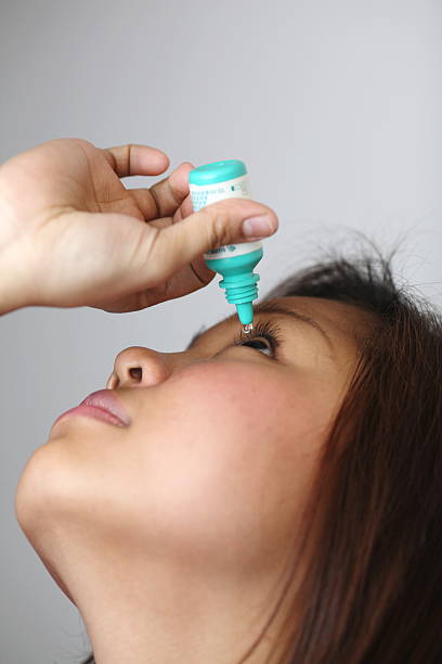 Closeup of doctor pouring eye drops in eye patient (conjunctivitis). Studio shot