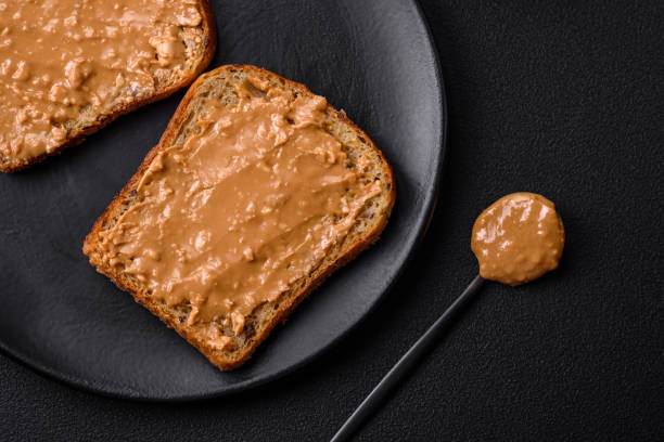 istock Nutritious sandwich consisting of bread and peanut butter on a black ceramic plate 1467684944