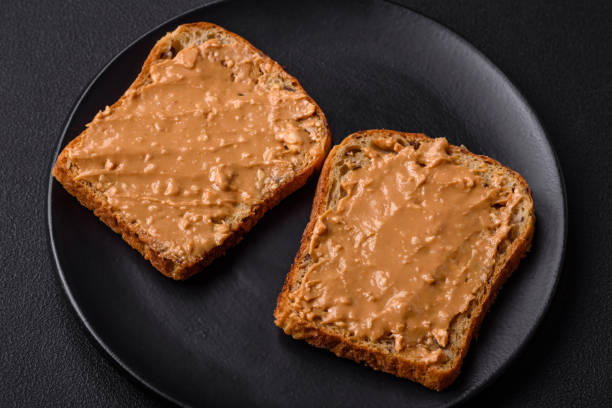 istock Nutritious sandwich consisting of bread and peanut butter on a black ceramic plate 1467684953