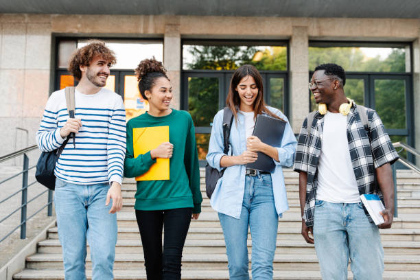 Happy students walking together on university campus, chatting and laughing outdoors after classes Happy students walking together on university campus, chatting and laughing outdoors after classes university student stock pictures, royalty-free photos & images