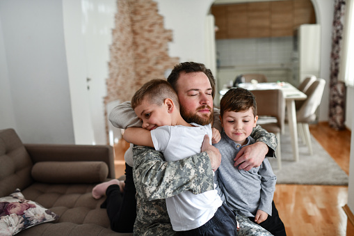 Children Embracing Father In Military Uniform And Praying For His Safe Return