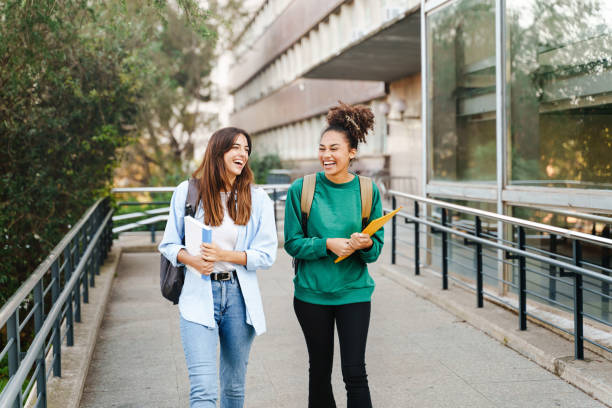 University student girl friends with learning books walking out School building University student girl friends with learning books walking out School building exchange student stock pictures, royalty-free photos & images