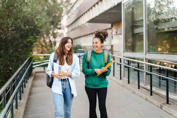 Photo of University student girl friends with learning books walking out School building