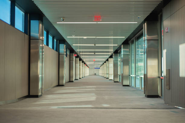 istock corridor of empty building with exit signs lit in red and windows on one side, during the day 1467688349