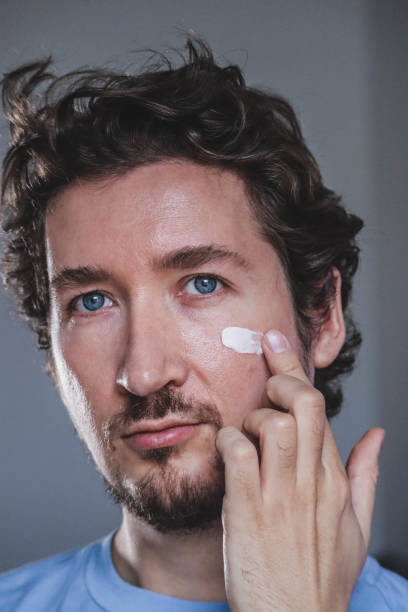 istock Handsome young man applying cream on his face 1467688735
