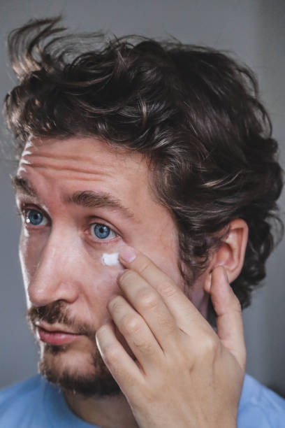 istock Handsome young man applying cream on his face 1467688932
