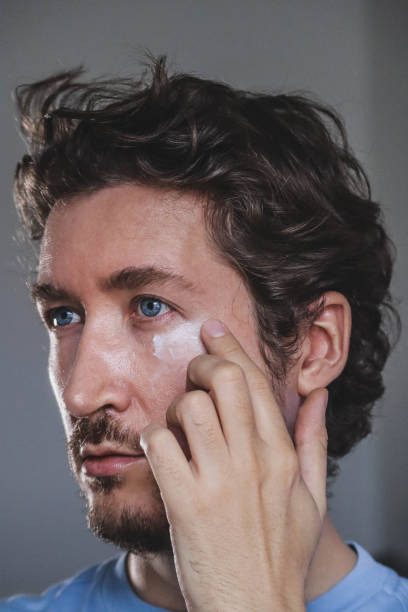 istock Handsome young man applying cream on his face 1467688937