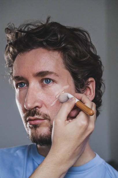 istock Handsome young man applying foundation to his face with a brush 1467689737