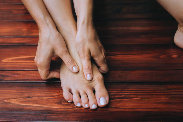 A two woman's hand massages her own foot. The concept of leg fatigue, spasms, cramps. Hygiene and health. stock photo