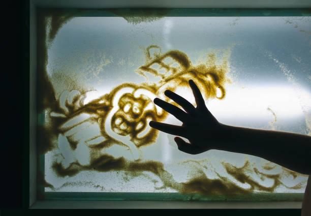 The hand of a little girl draws on a light table with sand. The concept of children's creativity. stock photo