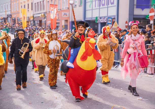los participantes del tradicional desfile del festival en austria visten ropa colorida y de disfraces mientras se mueven por las calles de villach durante el evento anual fasching - fasching fotografías e imágenes de stock