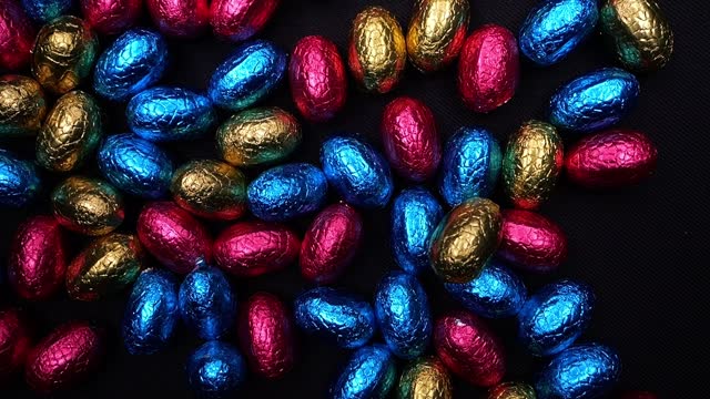 Chocolate Easter eggs in coloured silverware. Easter eggs tossing, rolling, jumping, dancing.