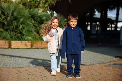 A brother and sister are chasing each other outside on a sunny spring day.