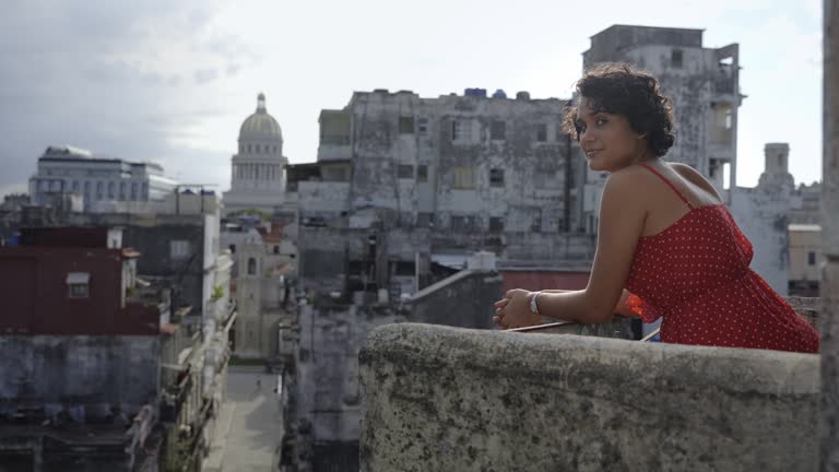 Young Latin American woman contemplating Havana city from balcony At Home in Cuba