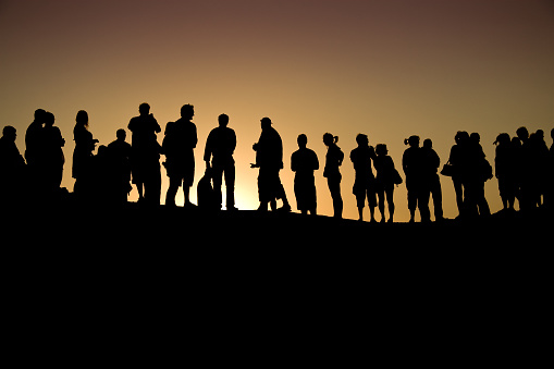 Silhouette of a diverse group of people against a sunset.