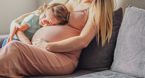 Little baby girl relaxing on mom's pregnant belly - Pregnant mother with a toddler - Family concept