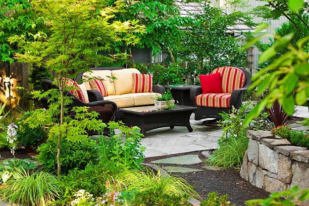 A scenic Danish garden featuring elegant outdoor furniture surrounded by dense, vibrant vegetation and beautifully blossoming flowers. Perfectly manicured plants and serene atmosphere create a tranquil outdoor oasis, ideal for relaxation.
