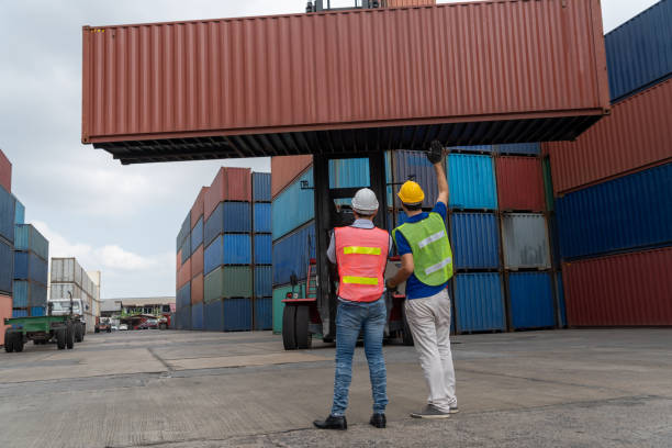 istock Industrial worker works with co-worker at overseas shipping container yard . Logistics supply chain management and international goods export concept . 1467713653