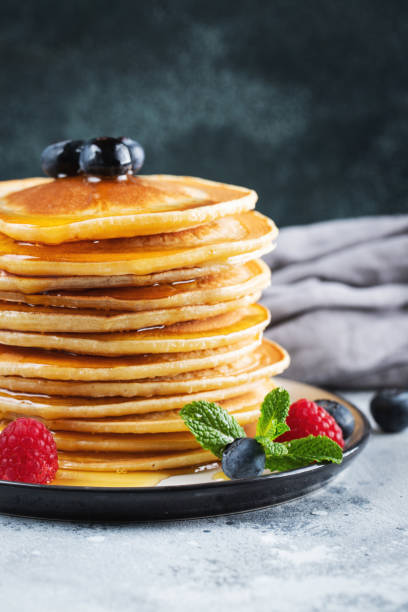 istock Delicious pancakes, with fresh blueberries, raspberry and maple syrup or honey on a dark background 1467713659