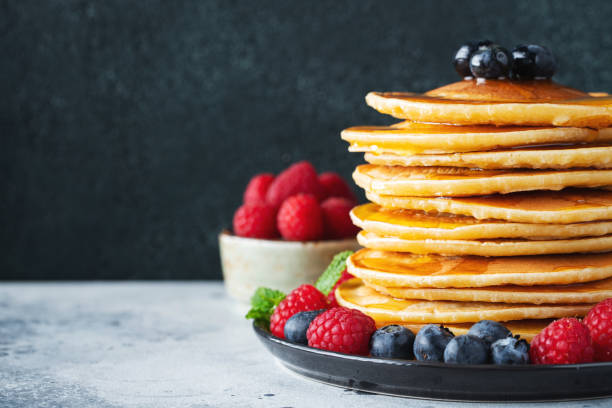 istock Delicious pancakes, with fresh blueberries, raspberry and maple syrup or honey on a dark background 1467713667