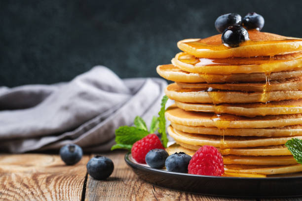 istock Delicious pancakes, with fresh blueberries, raspberry and maple syrup or honey on a dark background 1467713669