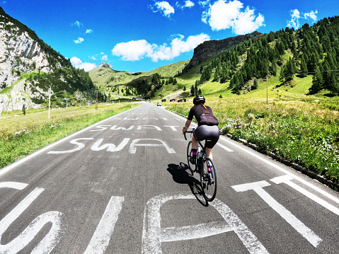 Young woman cycling around Dolomites in Italy (text on the street has been modified)
