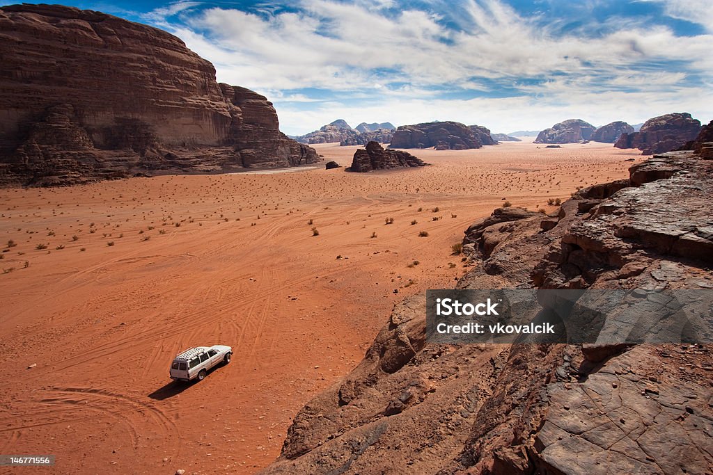 White jeep between the mountains in Wadi Rum, Jordan. Anonymous car in the sand of Wadi Rum reservation, Jordan. 4x4 Stock Photo