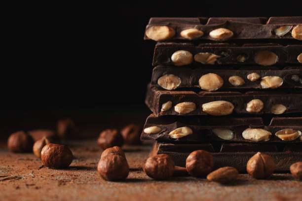 istock Dark and milk chocolate with nuts on a dark background sprinkled with cocoa powder. 1467718431