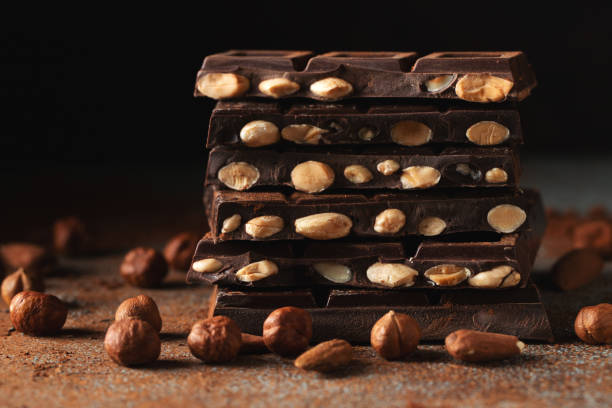 istock Dark and milk chocolate with nuts on a dark background sprinkled with cocoa powder. 1467718435