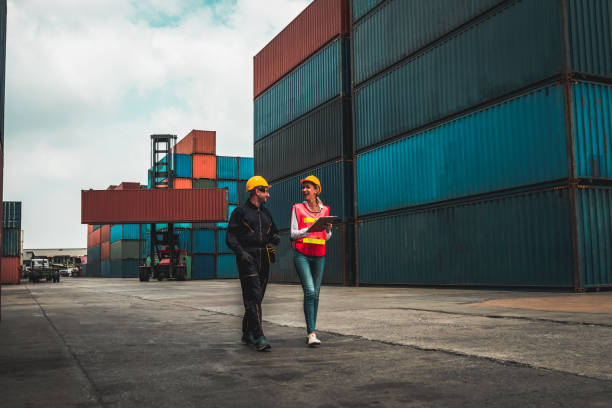 istock Industrial worker works with co-worker at overseas shipping container yard . Logistics supply chain management and international goods export concept . 1467722740
