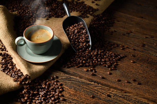tazza di caffè con fumo e chicchi di caffè su vecchio sfondo di legno - fresh coffee foto e immagini stock