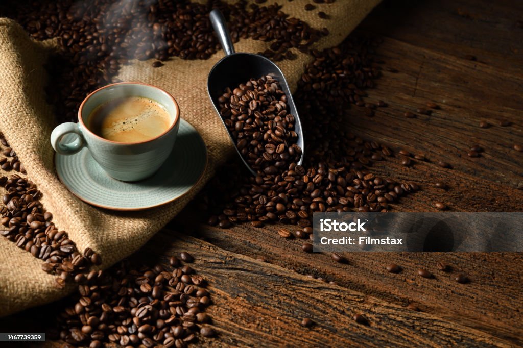 Cup of coffee with smoke and coffee beans on old wooden background Coffee - Drink Stock Photo