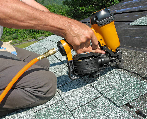 Carpenter uses nail gun Carpenter uses nail gun to attach asphalt shingles to roof wood shingle photos stock pictures, royalty-free photos & images
