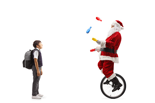 Boy standing and watching santa claus riding a mono cycle and juggling isolated on white background