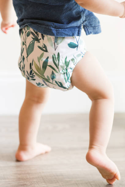 istock A 1-Year-Old Baby Boy Playing on the Floor & Learning to Walk While Wearing Just a Cloth Diaper With a Leaf Pattern & a Blue Shirt 1467743981